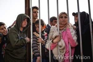 食料配布の様子を柵越しに見守るシリア難民の子どもたち