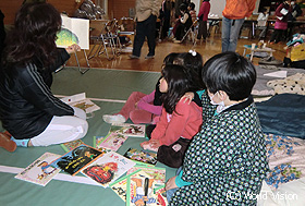 避難所の近所女性の絵本の読み聞かせに聞き入る避難所の子どもたち