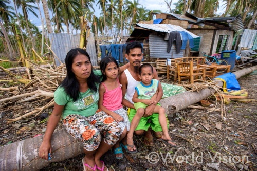 フィリピンの被災した家族と後ろが家族の仮設住宅