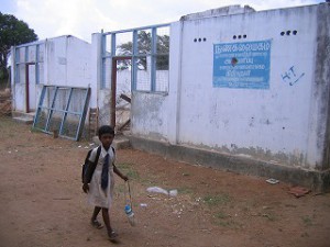 破損した建物の前を通学する少女