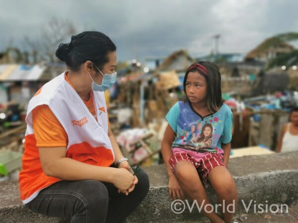 台風の被害を受けた子どもと、 寄り添うワールド・ビジョンのスタッフ(フィリピン)