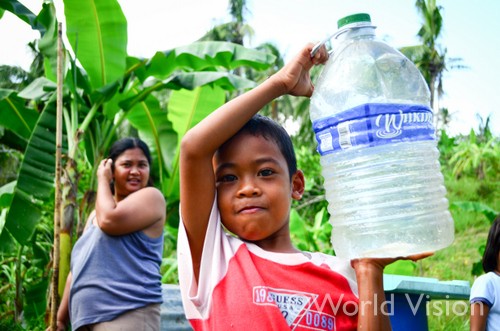 家族で飲む水を運ぶアレクサンダー君（６）。台風発生直後、ワールド・ビジョン・ジャパンはライフラインが破壊された地域に安全な水を届けた
