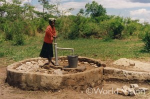 まだ完成前の井戸で早くも水を汲む村の女性