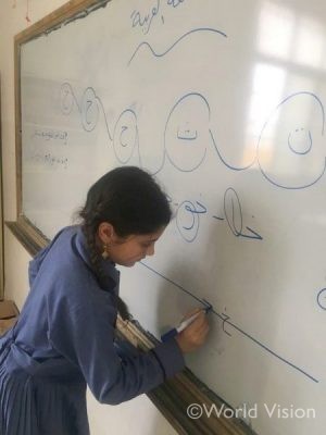 補習授業でアラビア語のアルファベットの書き方を練習している女の子